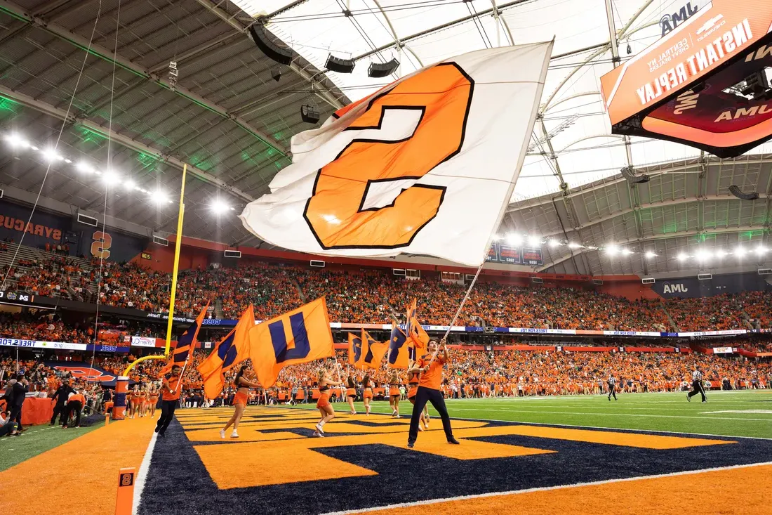 Student waving a Syracuse University flag during a game in the JMA Wireless Dome.